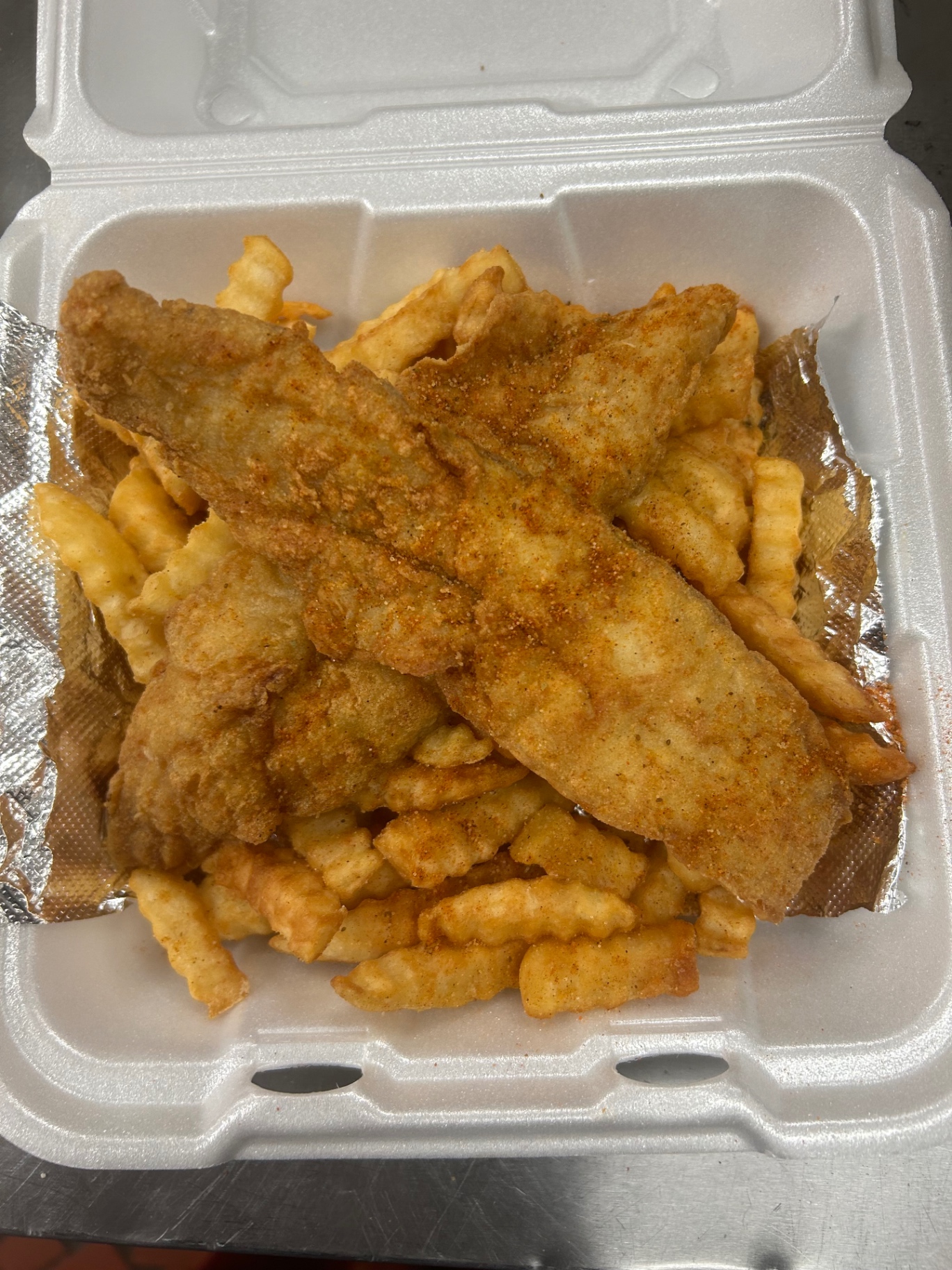 Fried fish fillets served over a bed of crinkle fries